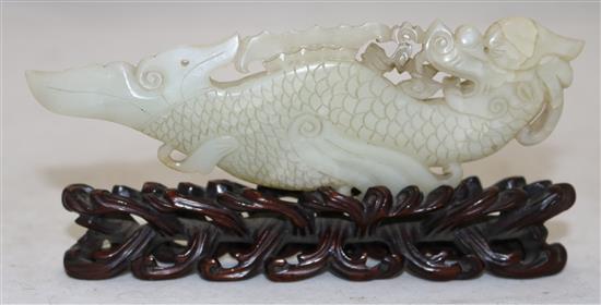 A Chinese pale celadon jade fish-dragon plaque, 18th century, 14cm, with a rosewood stand carved as waves